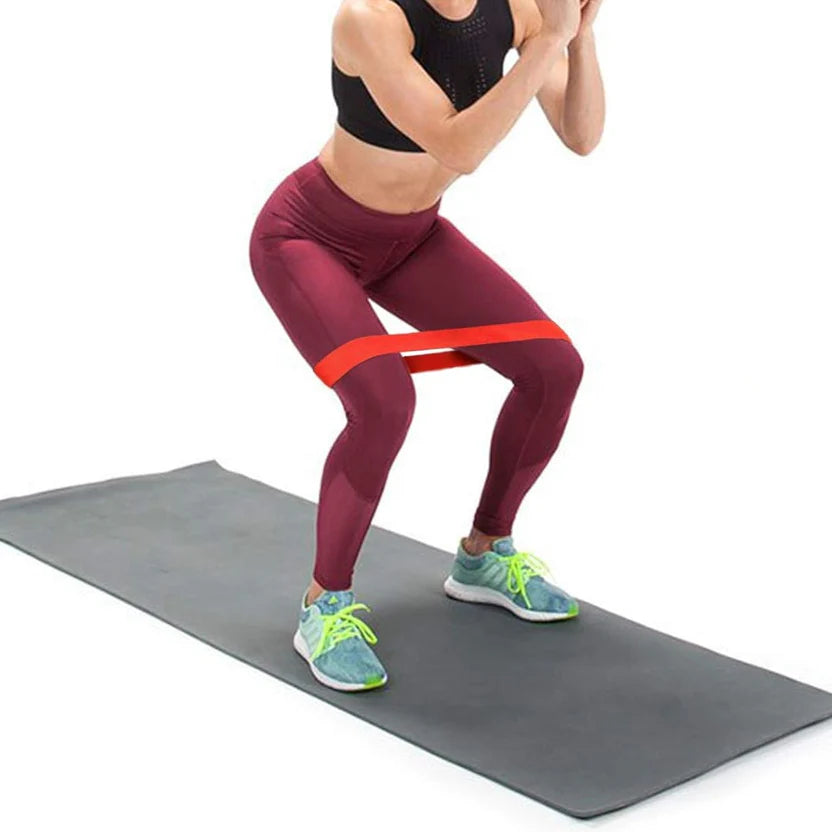 Person exercising with resistance band on a gray mat