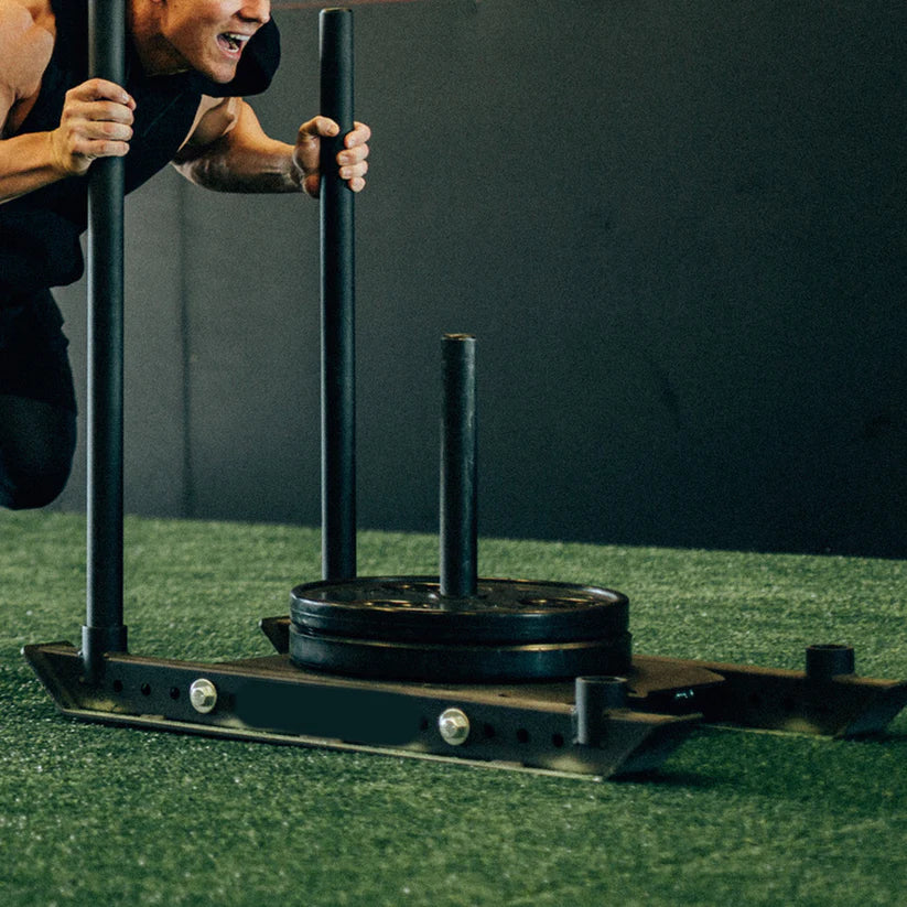Person using a weightlifting platform with weights on a green surface